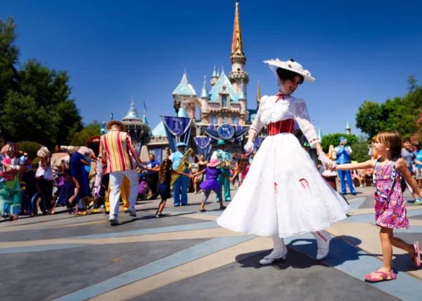 Disney character holding a little girl's hand in front of Disney castle